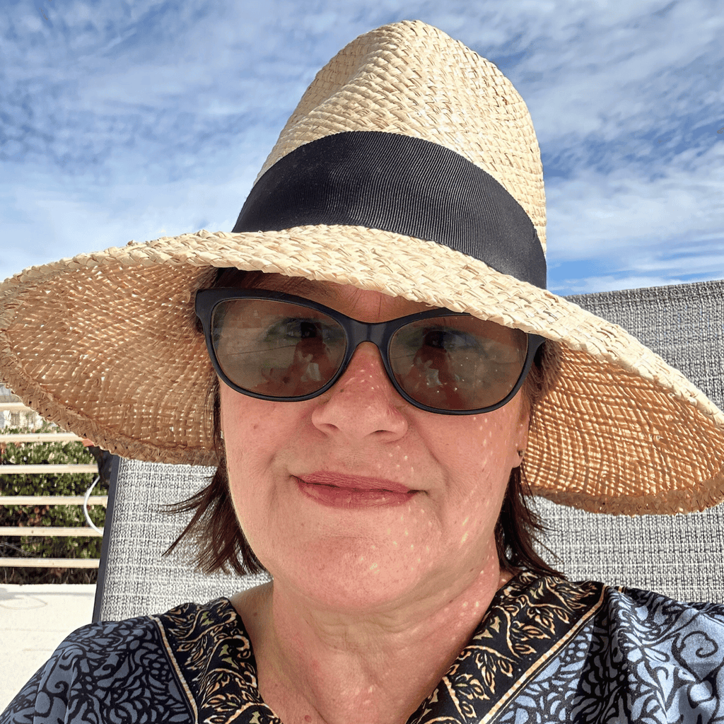 Person wearing a wide-brimmed straw hat with a black band against a blue sky.