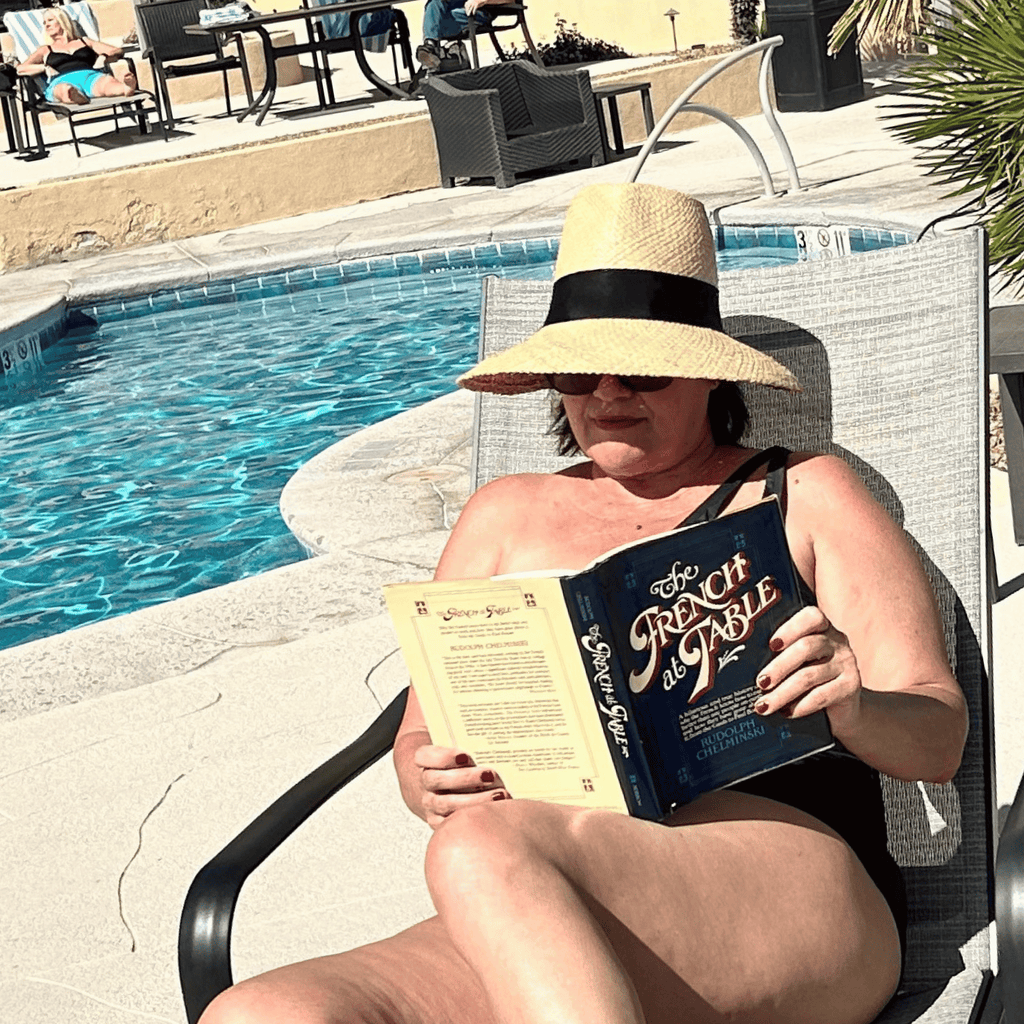 Person reading a book by a poolside